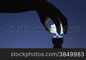 Doppelwendel-Energiesparlampe eindrehen, blauer Hintergrund