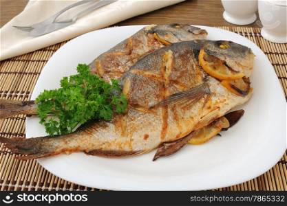 Dorado baked fish with lemon on a plate close-up
