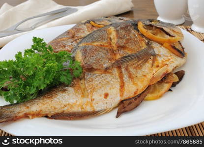 Dorado baked fish with lemon on a plate close-up