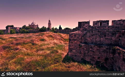 Dormition Abbey on Mount Zion in Jerusalem. Old City of Jerusalem, Israel. The green hill surrounded by the ramparts with the Dormition Abbeyat at sunset