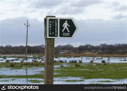 Dorset County Council footpath sign, flooded Christchurch meadows in background. Dorset, England, United Kingdom.