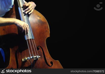 Double bass. The musician playing contrabass musical instrument on black background.