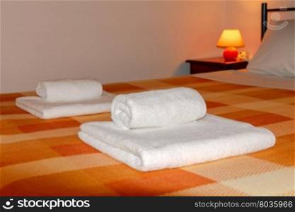 Double bed with orange blankets.. Beds with bed linen and towels.