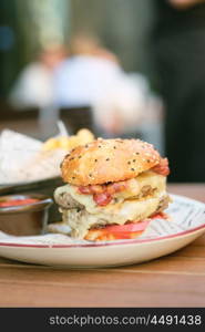 Double cheeseburger on table in outdoor restaurant with shallow depth of field