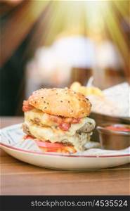Double cheeseburger on table in outdoor restaurant with shallow depth of field