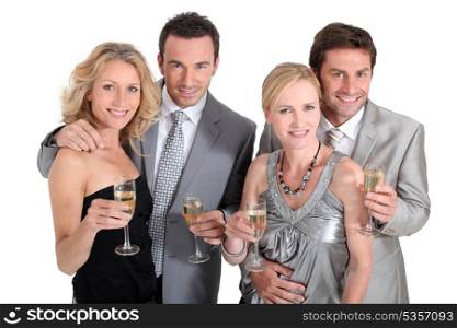 Double date: couples in party dress drinking champagne