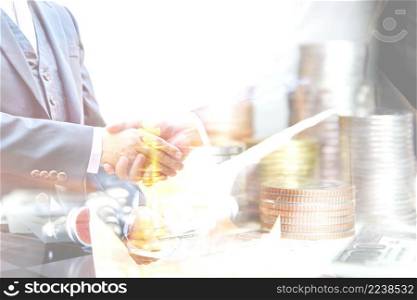 double exposure business men hand shake with coins stacking on Amrican dollar bank note , business concept