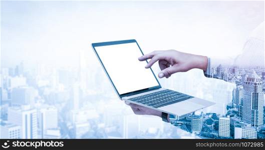 Double exposure image of businessman using computer on abstract modern city background. Future business and communication technology concept. Surreal futuristic multiple exposure graphic interface.
