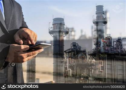 Double exposure of businessman checking oil refinery industry plant by smart phone in the night as Energy and Technology concept