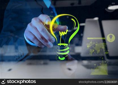 double exposure of businessman hand drawing light bulb on touch screen computer as success concept