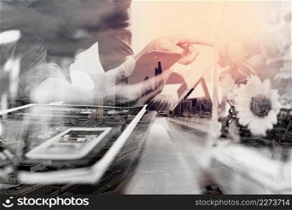 Double exposure of businessman hand using mobile payments online shopping,omni channel,laptop computer on wooden desk,glass vase flowers,London architecture buildings
