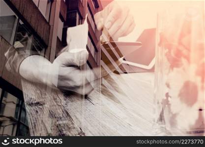 double exposure of businessman hand with pen using smart phone,mobile payments online shopping,omni channel,digital tablet docking keyboard computer,flower glass vase on wooden desk,London architecture city