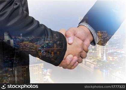 Double exposure of businessman handshake on blurred cityscape background.. businessman handshake