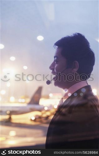 Double exposure of businessman with headset and airport