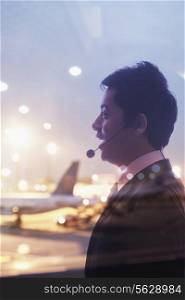 Double exposure of businessman with headset and airport