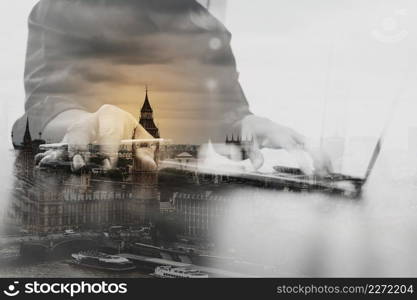 Double exposure of close up of business man hand working on laptop computer  with London architecture,building 