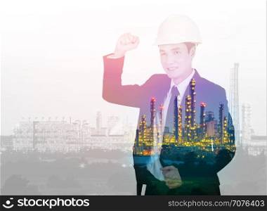 Double exposure of engineer celebrating with arm raised against the Petrochemical Industrial plant