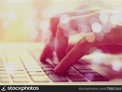 Double exposure of female hands typing on laptop with bokeh light