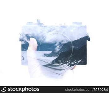 Double exposure of hand holding film camera and landscape background&#xD;