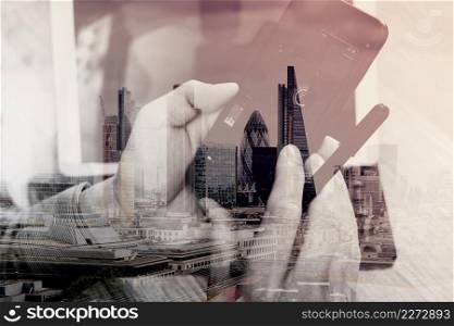Double exposure of Hand using mobile payments online shopping,omni channel,icon customer network,in modern office wooden desk,London city buildings,eyeglass
