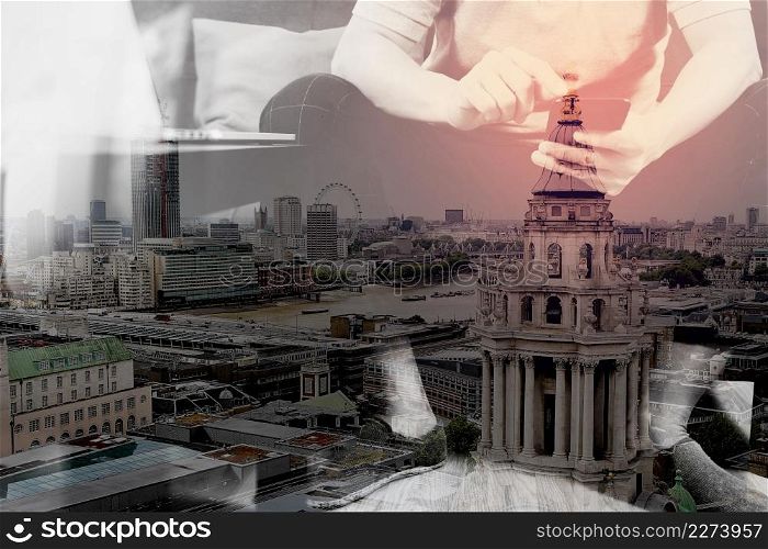 double exposure of hipster hand using digital tablet docking keyboard and smart phone for mobile payments online business,omni channel,sitting on sofa in living room,London architecture city