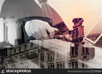 double exposure of justice and law concept.Male judge in a courtroom striking the gavel,working with digital tablet computer docking keyboard on wood table,London architecture city