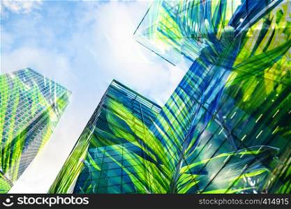 double exposure of modern skyscrapers windows and lush green vegetation - eco friendly green city