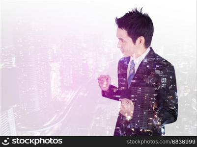 double exposure of successful business man with arm raised with a city background