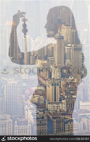 Double exposure of young woman holding Chinese ornament over cityscape