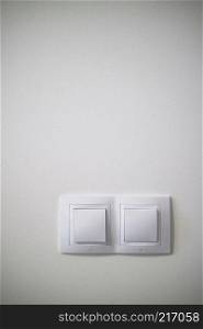 Double white lighting switchs on concrete wall, electrical power socket and plug switched with copy space. Electric two white lighting switchs on concrete wall