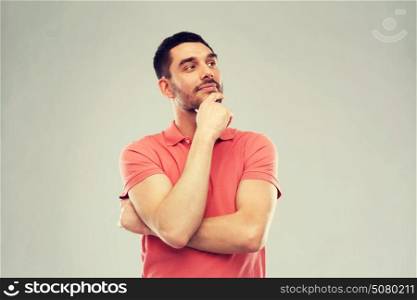 doubt, expression and people concept - man in polo t-shirt thinking over gray background. man in polo t-shirt thinking over gray background