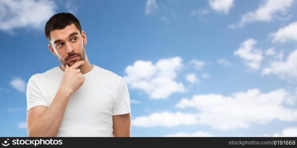 doubt, expression and people concept - man thinking over blue sky and clouds background