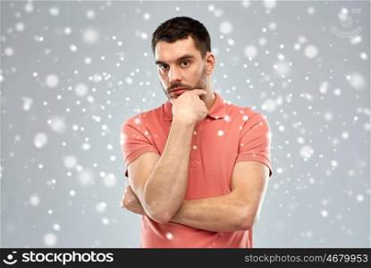 doubt, expression, winter, christmas and people concept - serious man thinking over snow on gray background