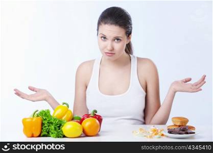 Doubting the girl with a healthy diet and sweet on a white background