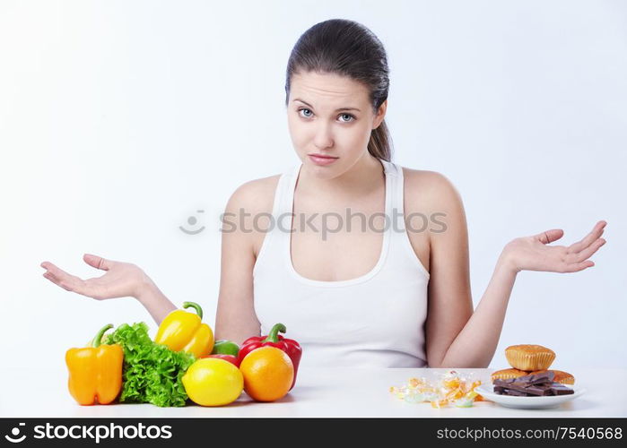 Doubting the girl with a healthy diet and sweet on a white background