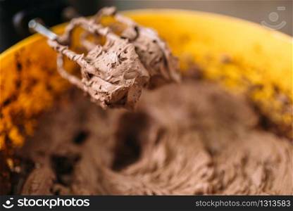 Dough and chocolate powder whipped in bowl with a mixer closeup view. Sweet cake ingredients preparation