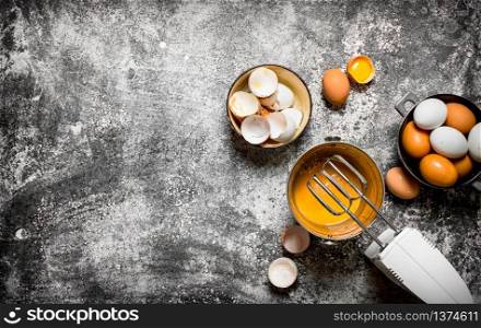 Dough background. Preparation of the dough. Whisking fresh eggs in the bucket mixer. On rustic background.