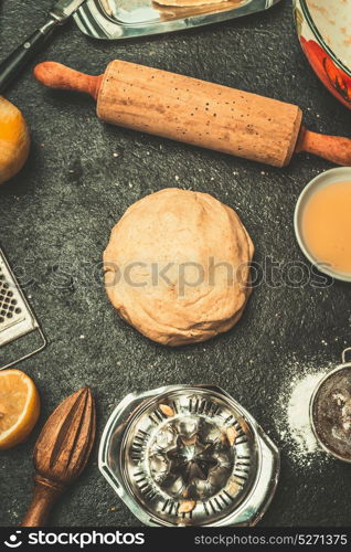 Dough for cookies or cake baking on dark kitchen table background with tolls and ingredients, top view