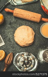 Dough for cookies or cake baking on dark kitchen table background with tolls and ingredients, top view