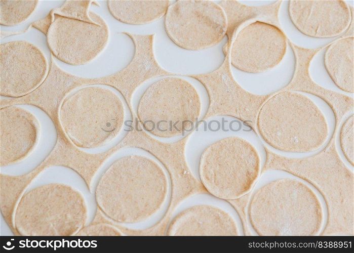 Dough for homemade pelmeni on white table. Process of making pelmeni, ravioli or dumplings with meat