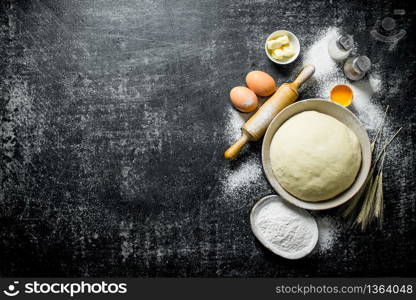 Dough in bowl with flour, eggs and butter. On dark rustic background. Dough in bowl with flour, eggs and butter.