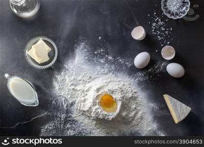 Dough on black table with flour and ingridients. Top view. Dough on black table with flour and ingridients