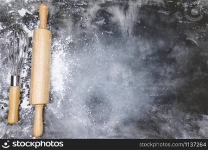 dough preparation recipe bread. equipment accessories baking ingredients bakery cooking. Egg whisk,rolling pin and flour. flat lay on table dark background. Top view, copy space.