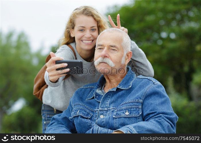 doughter and dad sitting in his wheelchair taking selfie