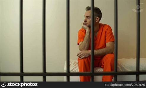 Downcast inmate sits behind bars in prison