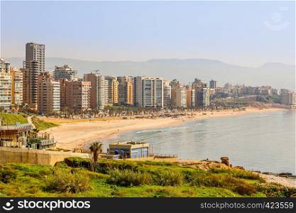 Downtown buildings and towers with road, sandy beach and sea in the foreground, Beirut, Lebanon