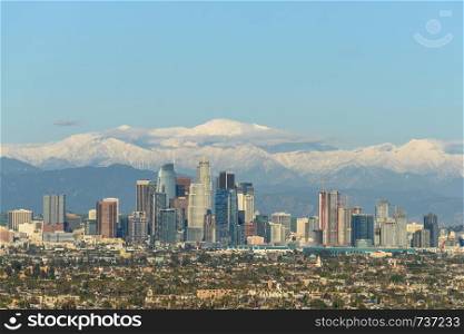 Downtown Los Angeles skyline with snow capped mountains behind at sunny day