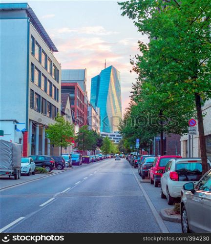Downtown street cityscape with cars parking and European Central Bank modern building in evening sunlight, Frankfurt am Main, Germany