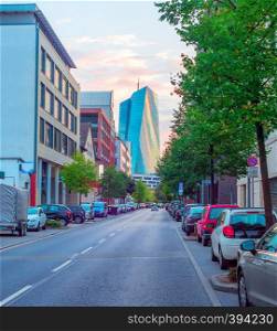 Downtown street cityscape with cars parking and European Central Bank modern building in evening sunlight, Frankfurt am Main, Germany