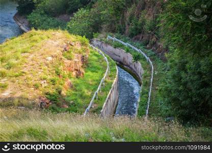 Drainage dam reservoir on hill with canal and drainage system water flow to river nature forest background